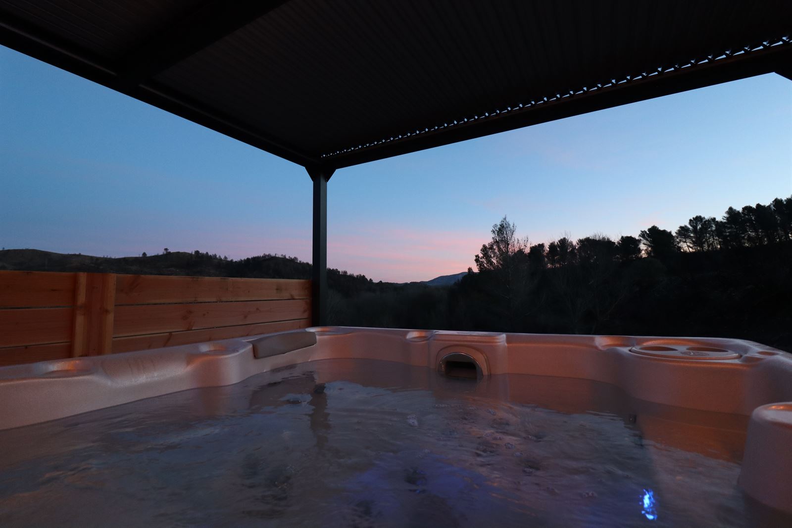 Jacuzzi sous la pergola de L'Amoré au coucher du soleil, face aux collines