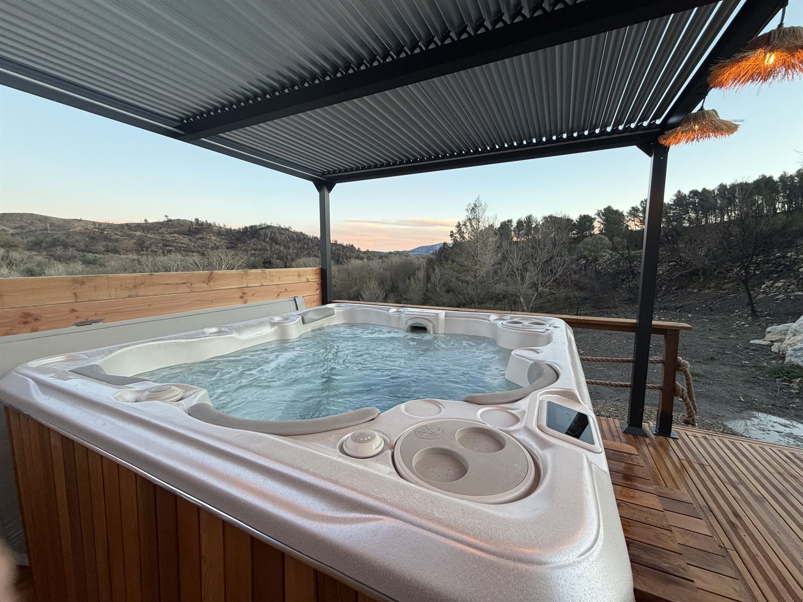 Jacuzzi de L'Amoré de jour sous la pergola, avec vue sur les collines
