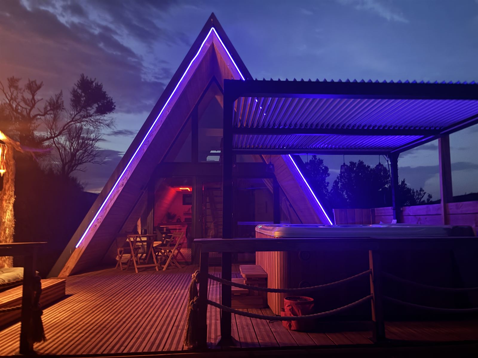 Terrasse et jacuzzi de L'Amoré sous un ciel violet à la tombée du jour