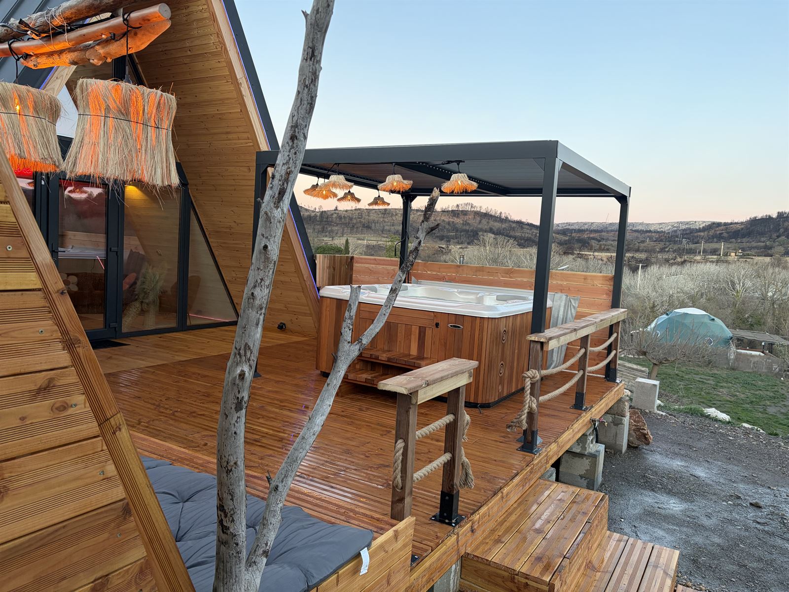 Terrasse de L'Amoré avec sa pergola et ses suspensions en raphia, le dôme visible au loin