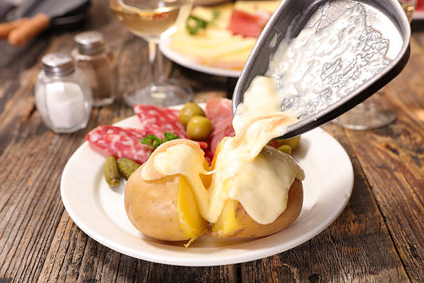 Raclette : fromage fondu versé sur une pomme de terre, avec charcuterie et cornichons