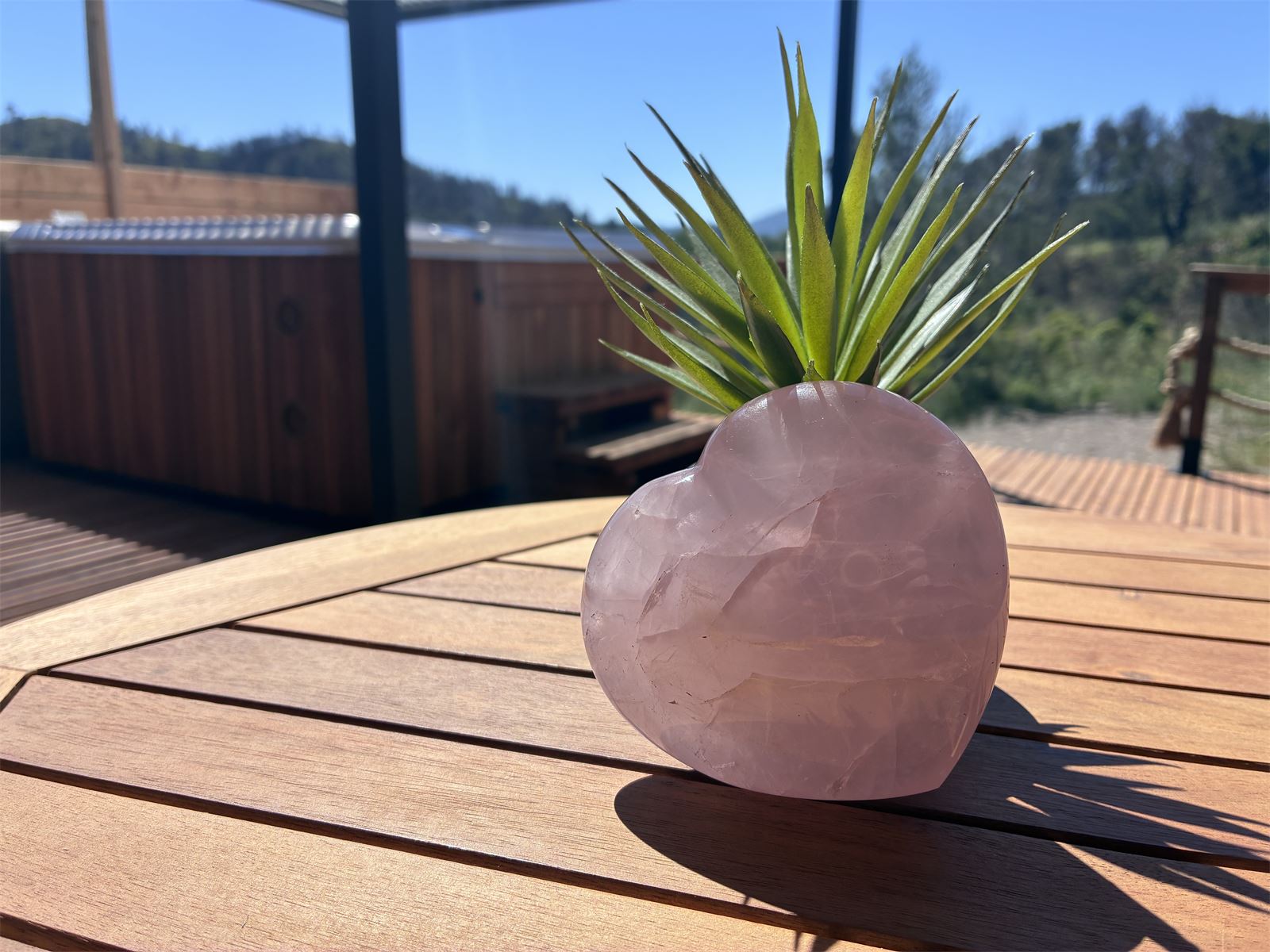 Cœur en quartz rose posé sur une table de terrasse